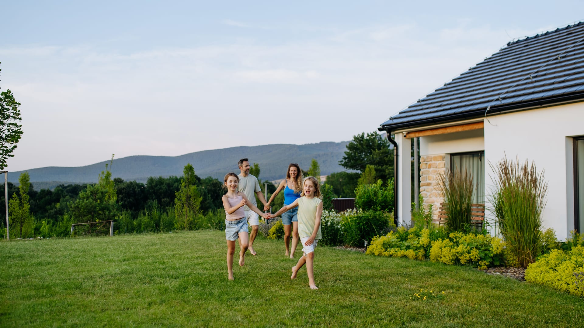 A family running across a green lawn beside a house. Illustrative photograph, not a specific listing.